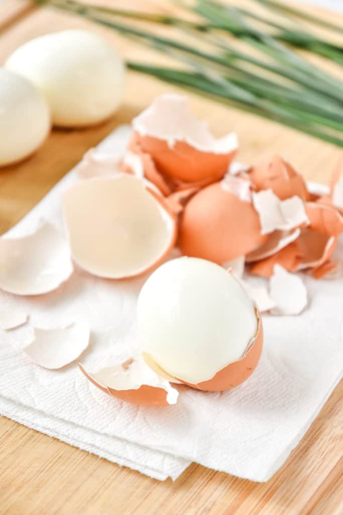 peeling hard boiled eggs on a cutting board.