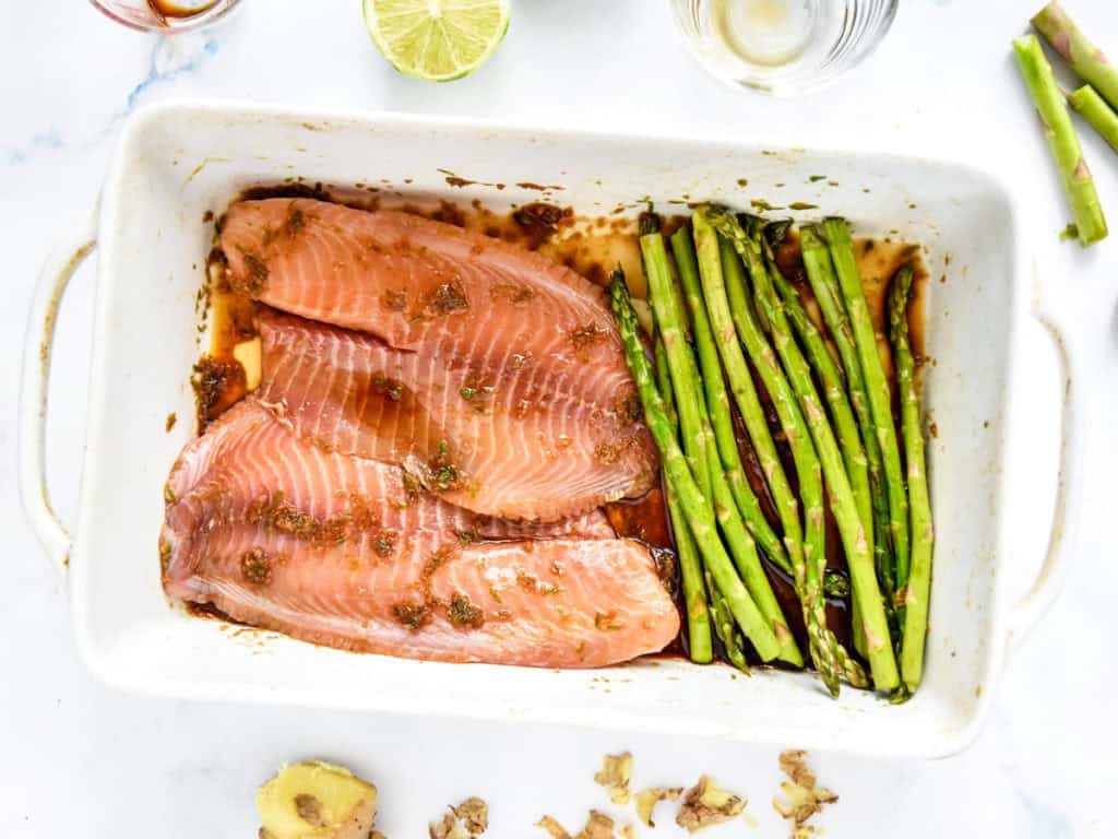 Ginger Soy Tilapia and Broiled Asparagus marinating in a baking dish before broiling.