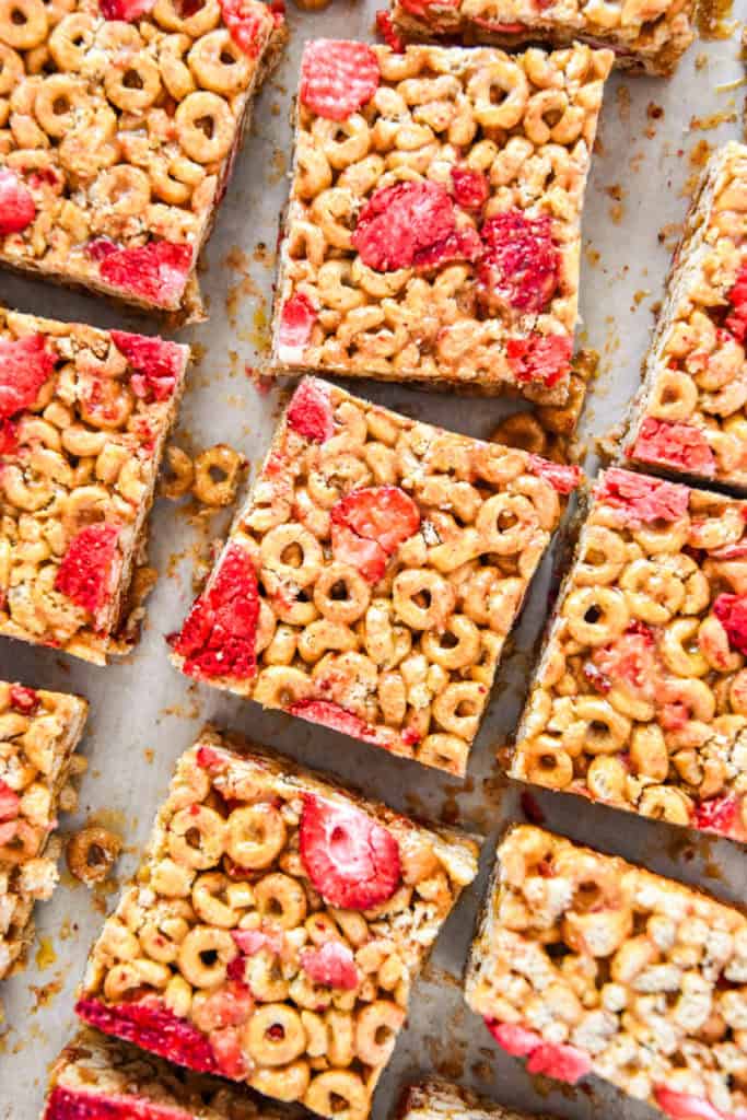 strawberry peanut butter cheerios bars cut on parchment paper.