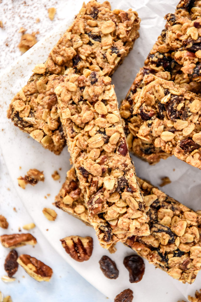 chewy cinnamon granola bars stacked on white parchment paper.