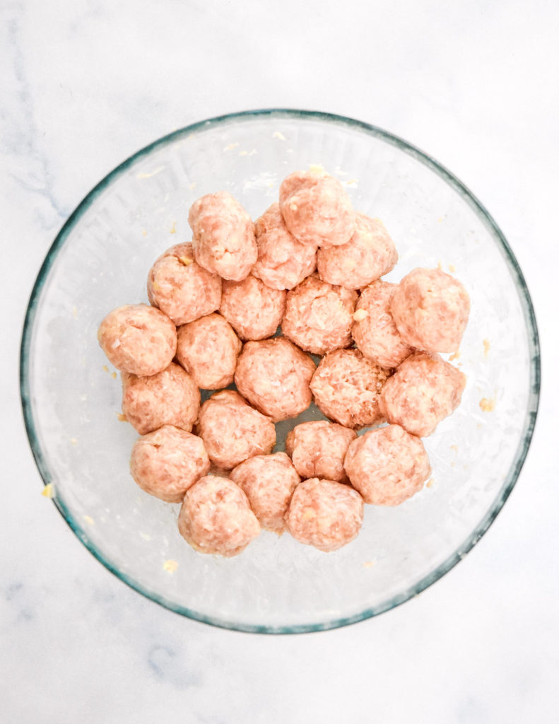 raw formed chicken meatballs in a glass bowl.