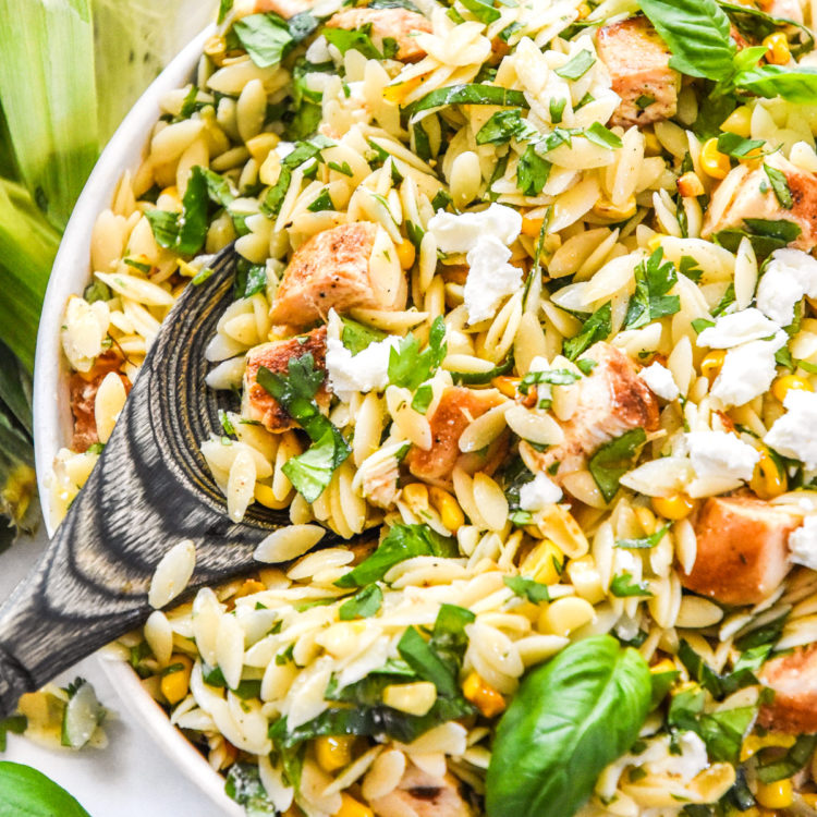 lemony chicken and corn orzo salad with fresh herbs and crumbled goat cheese on top.