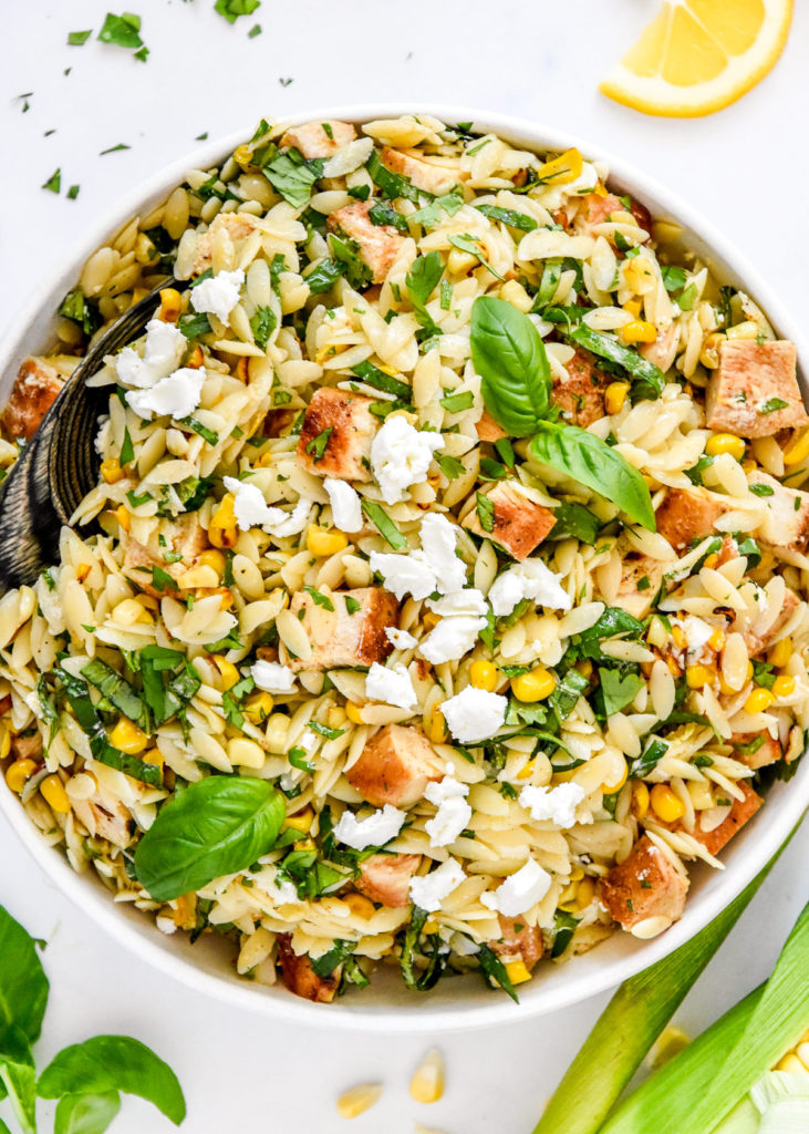 lemony chicken and corn orzo salad with fresh herbs and crumbled goat cheese on top.