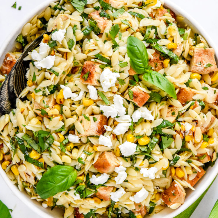 lemony chicken and corn orzo salad with fresh herbs and crumbled goat cheese on top.