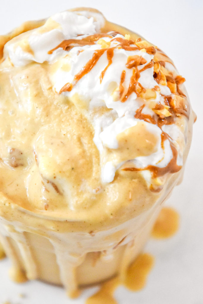 close up of peanut butter powder milkshake in a clear cup.