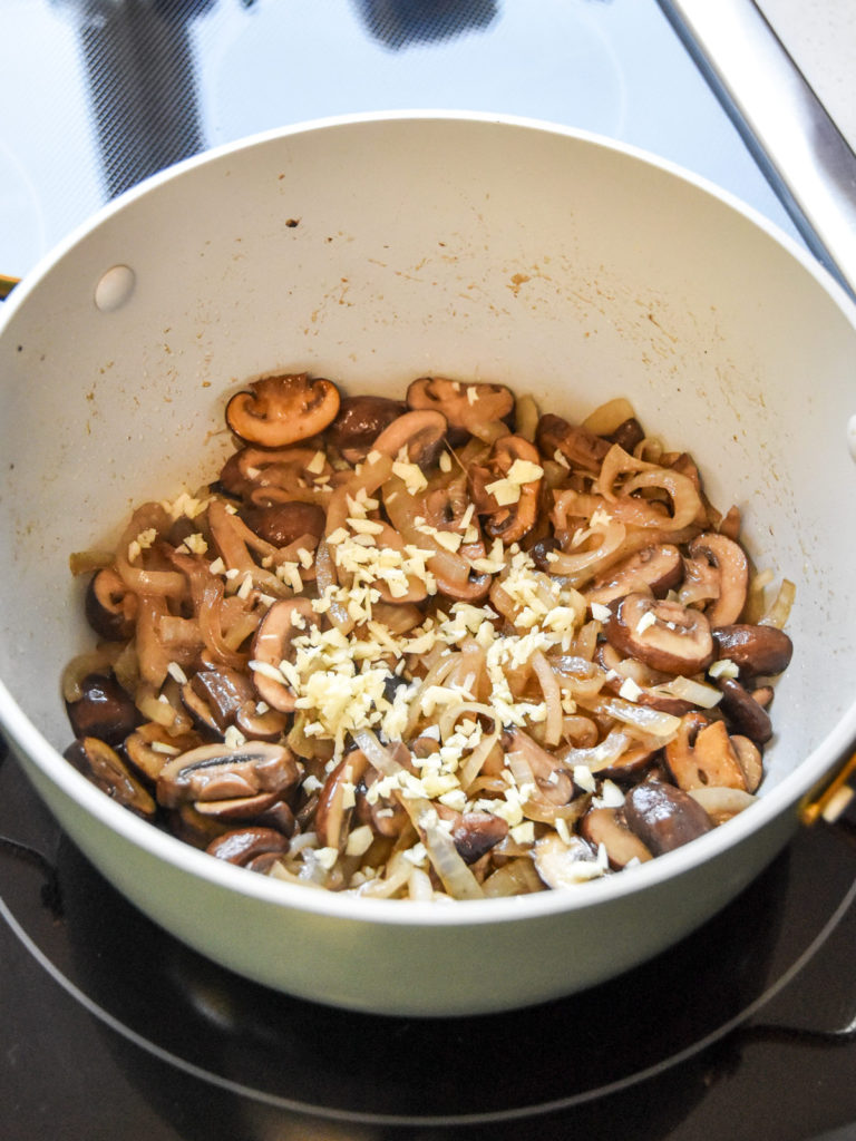 garlic onions and mushrooms cooking in a pot on the stove.