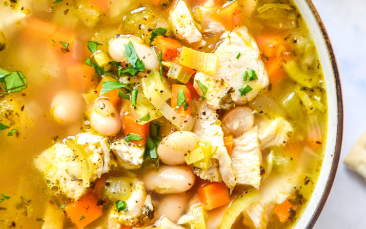 white bean lemon chicken soup in a bowl with a gold spoon.