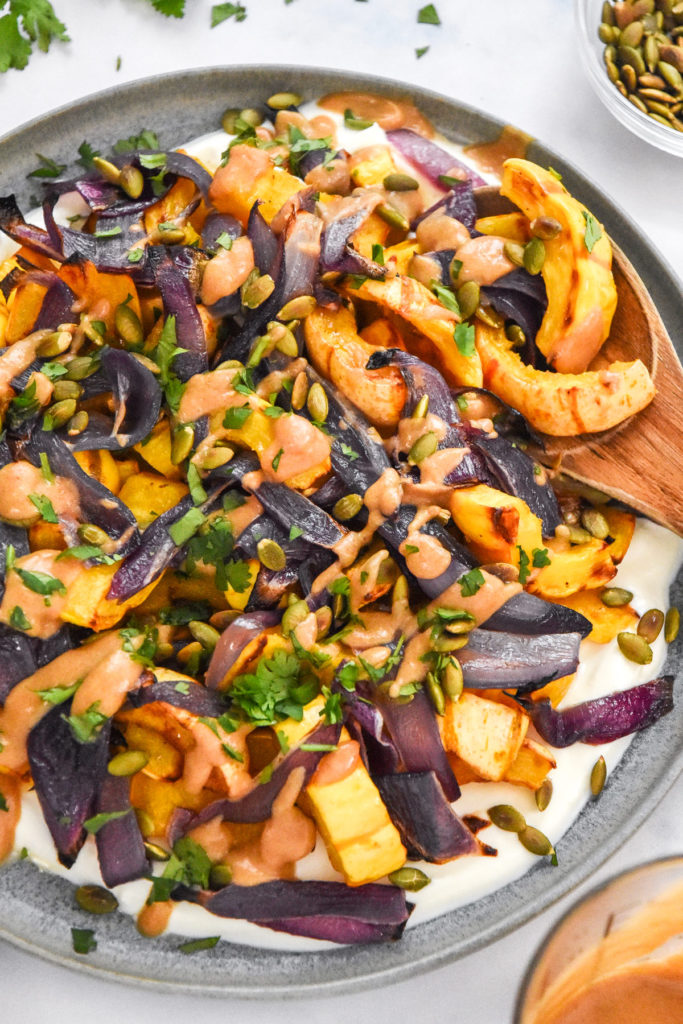 roasted squash salad with whipped feta plated with a wooden serving spoon.