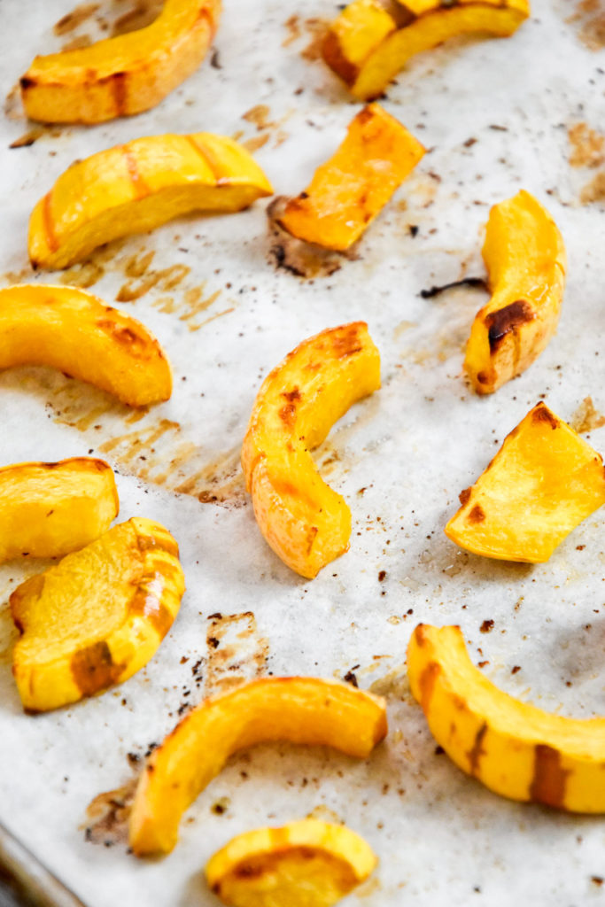 roasted delicata squash on a sheet pan with parchment paper.