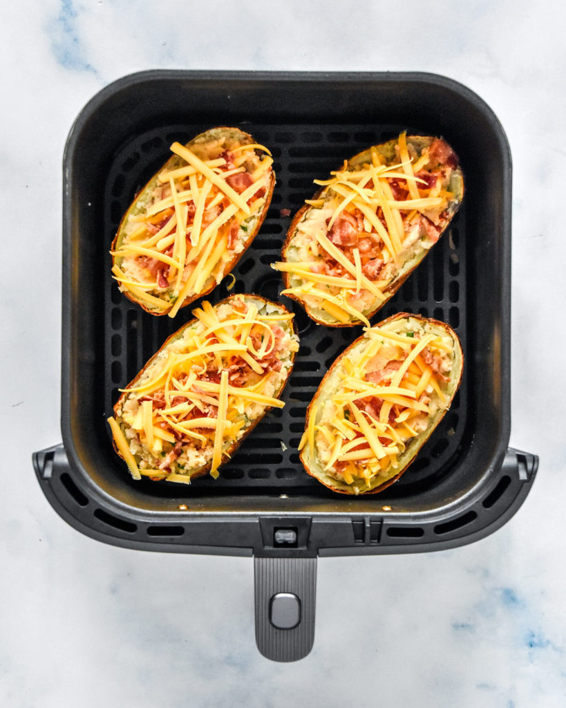 air fryer twice baked potatoes with toppings in the air fryer basket before baking again.