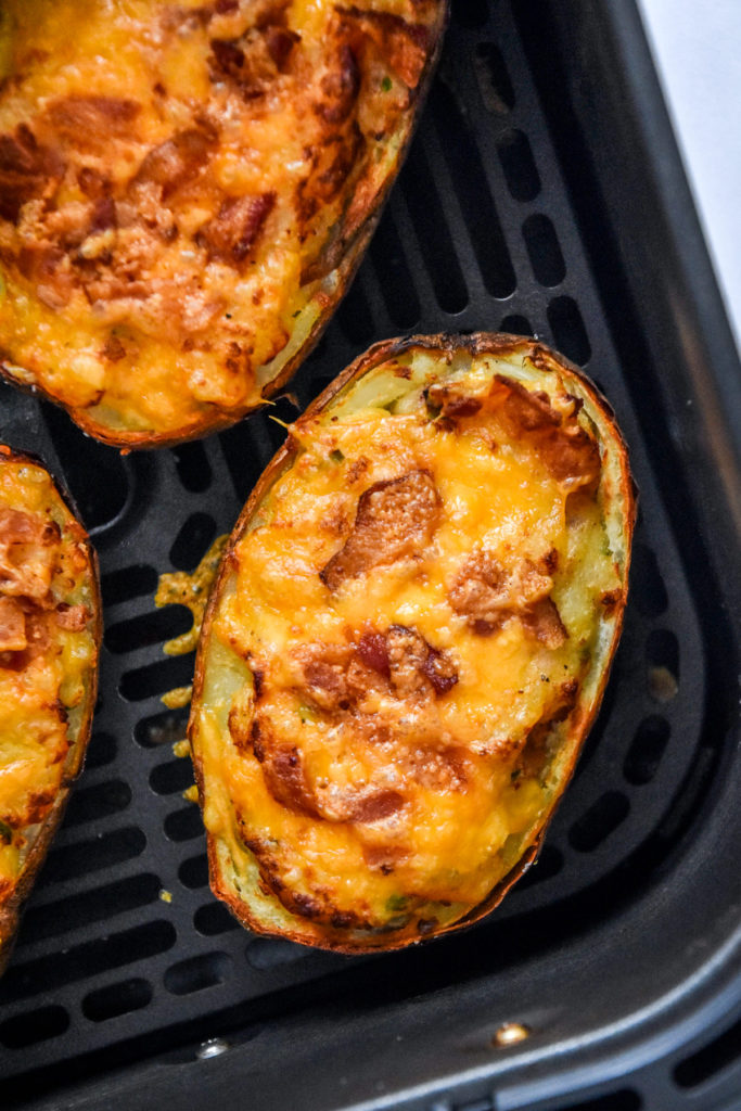 air fryer twice baked potatoes in the basket with golden crispy cheese on top.