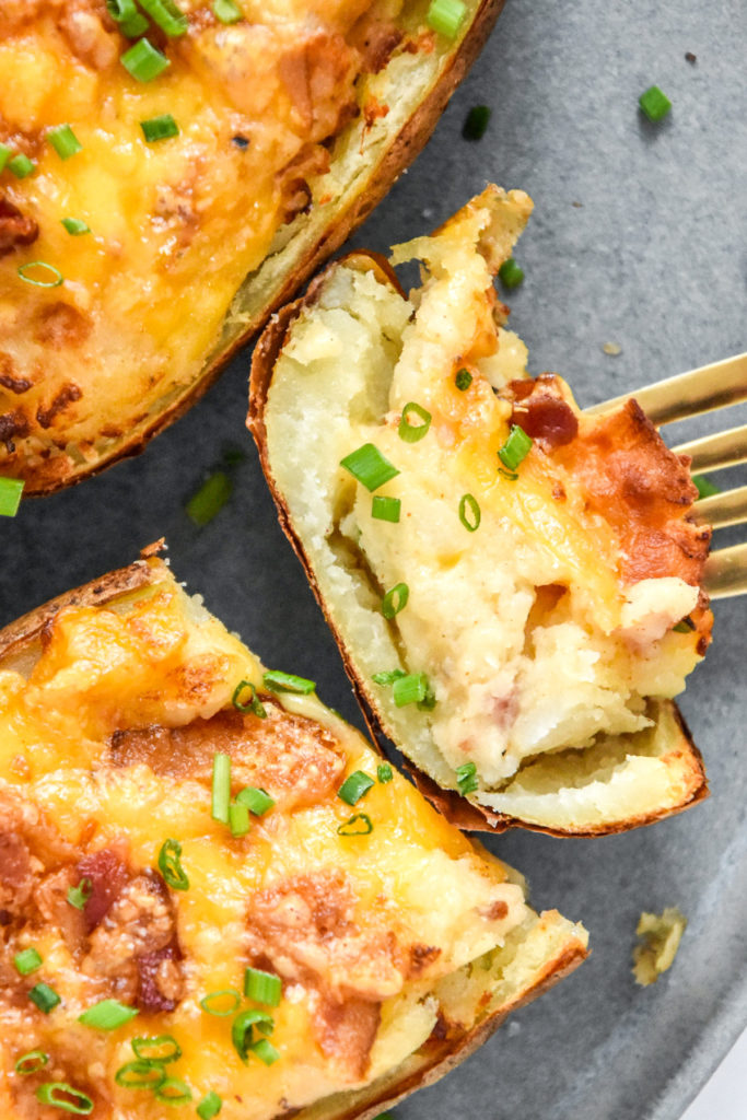 cooked air fryer twice baked potatoes with one sliced open.