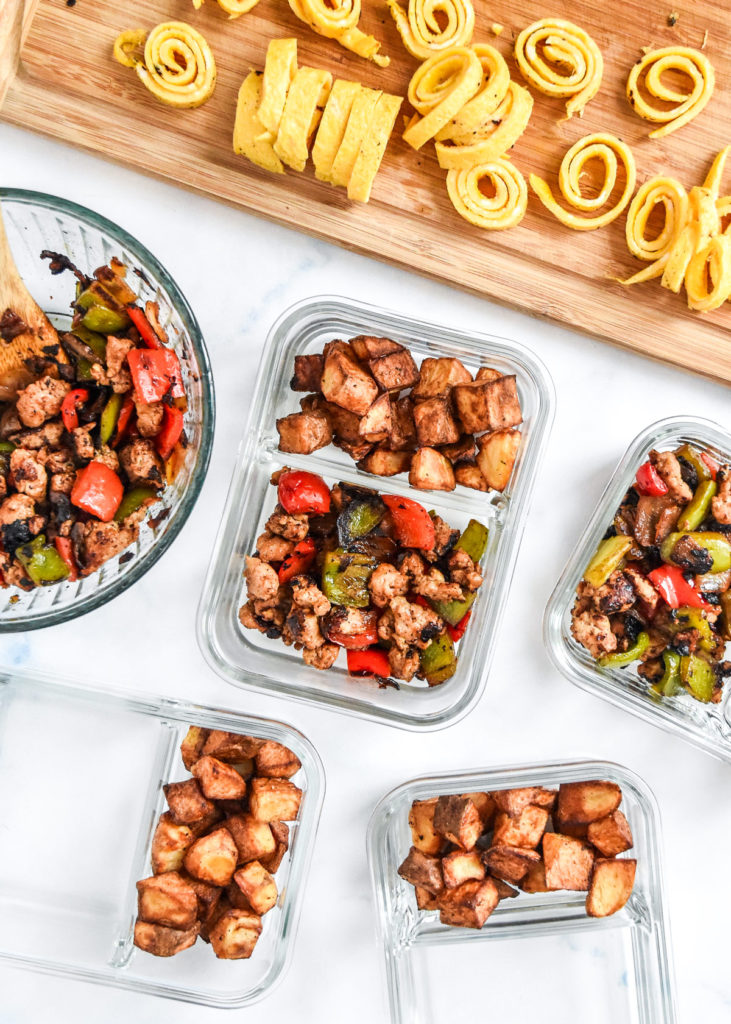 assembling the crispy potato egg ribbon breakfast bowls into glass meal prep containers.