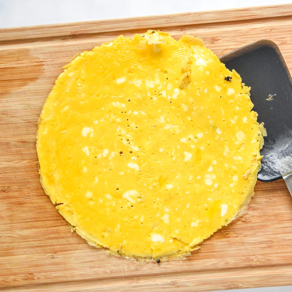 a cooked flat egg pancake on a cutting board.