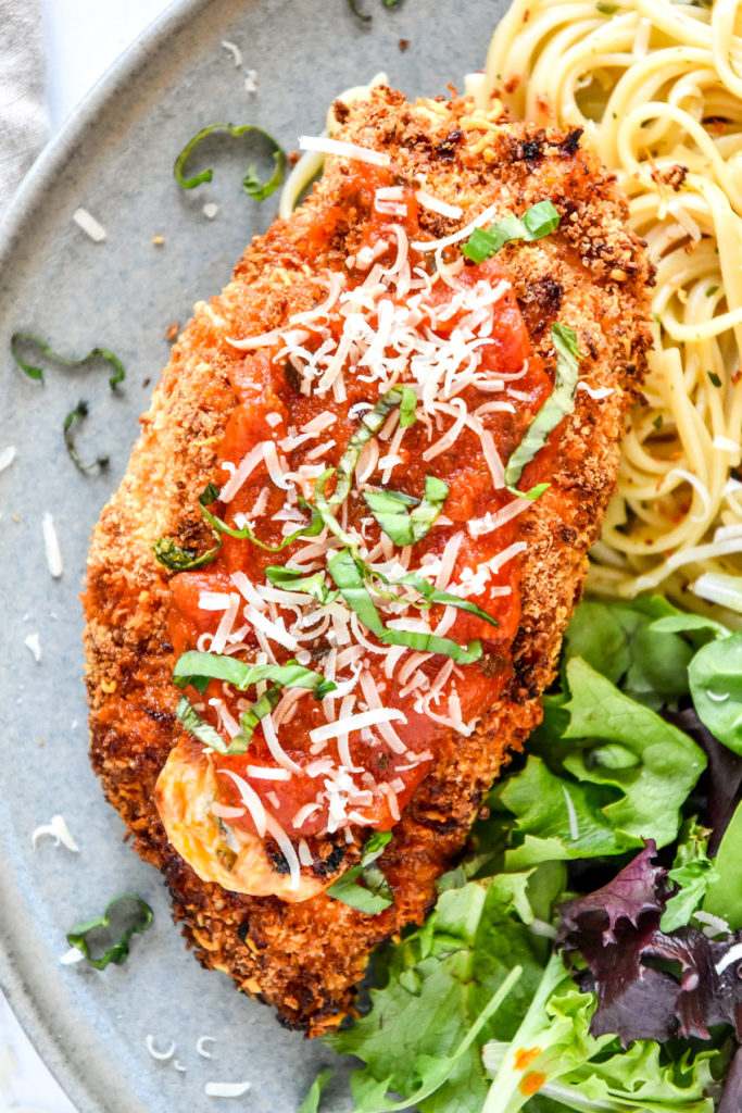 air fryer stuffed chicken parmesan with marinara and fresh basil on top.