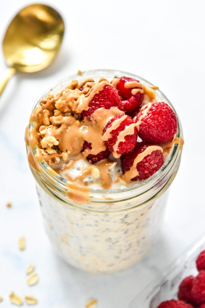 protein overnight oats base recipe with raspberries and peanut butter drizzle on top.