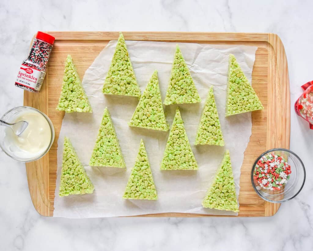 green rice krispies treat christmas trees on a cutting board before being decorated.