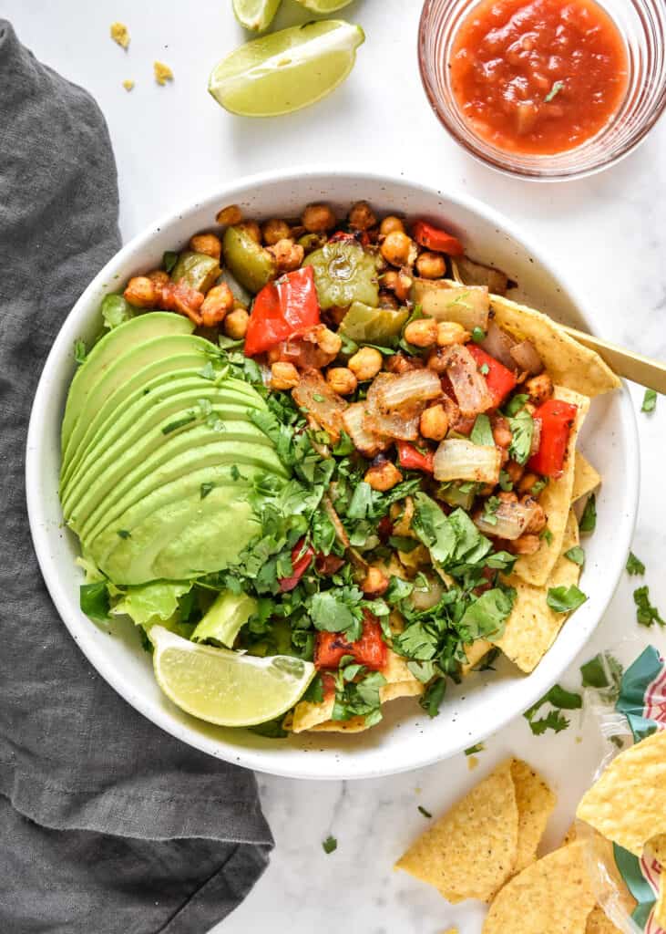 roasted chickpea taco salad bowls with avocado, cilantro and lime on top.