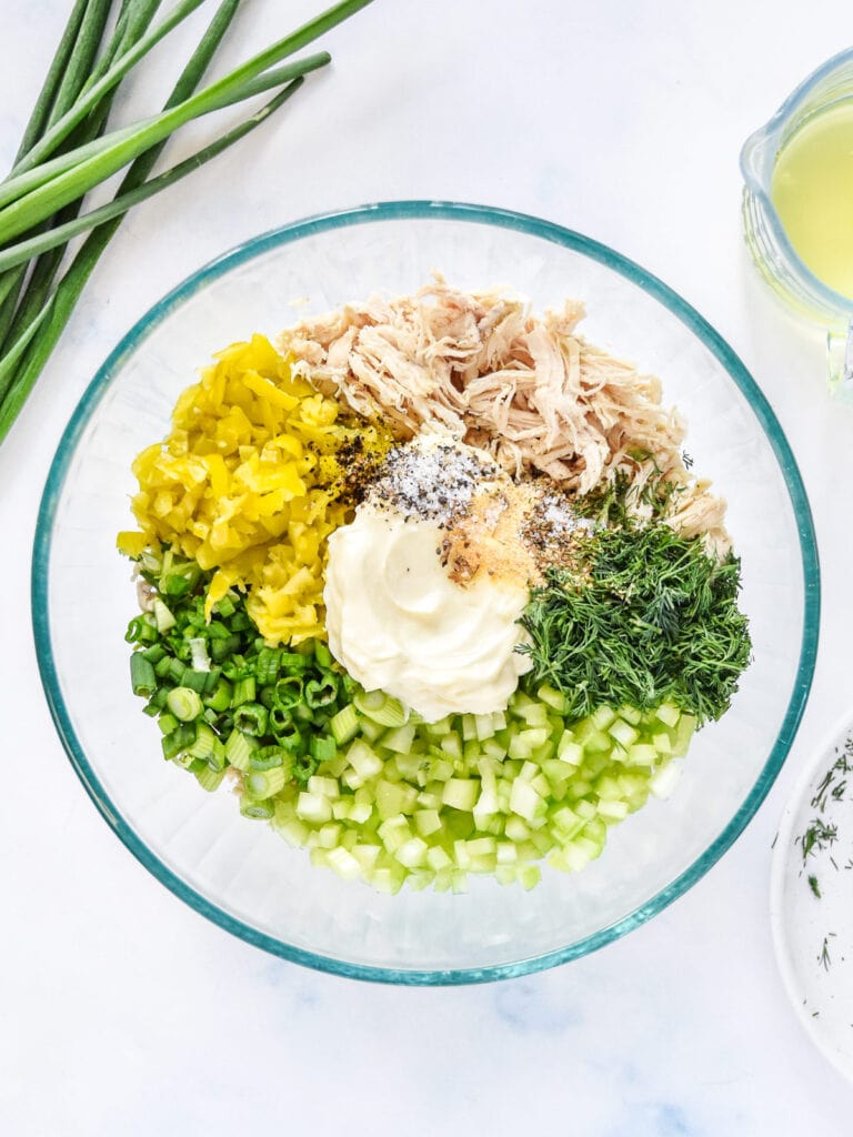 ingredients for the pepperoncini chicken salad in a glass mixing bowl before mixing.