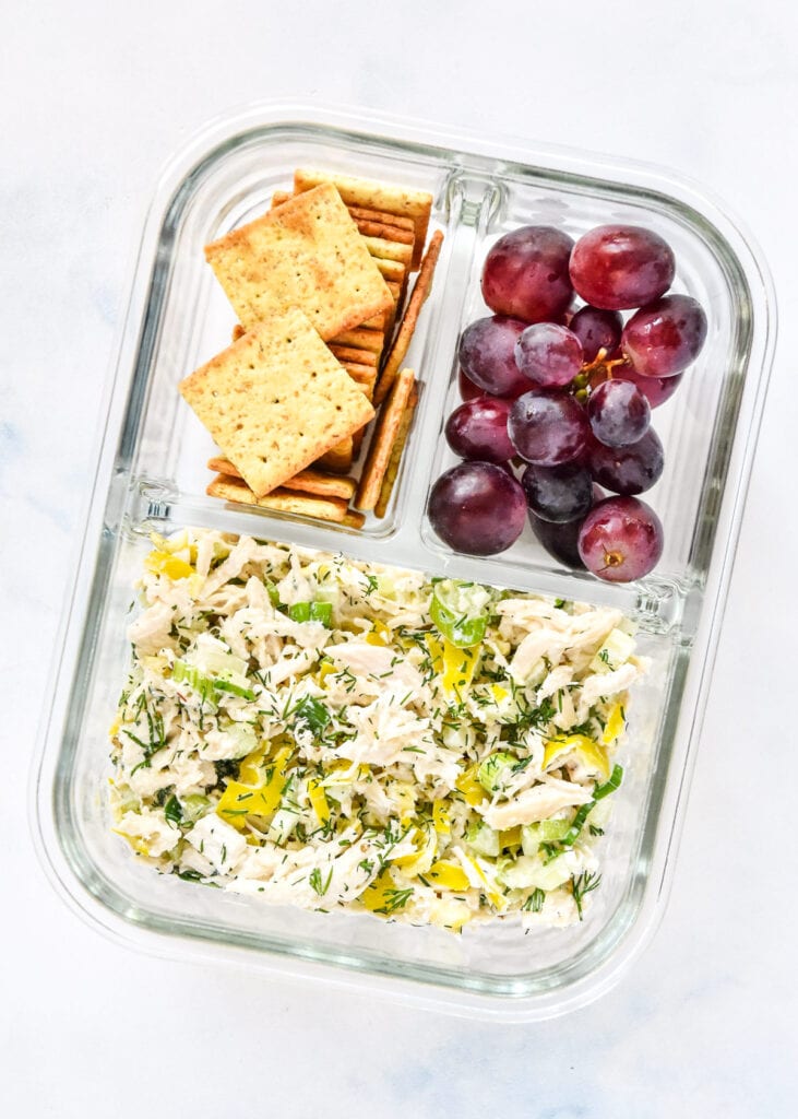 zesty pepperoncini chicken salad with crackers and grapes in a glass meal prep container.