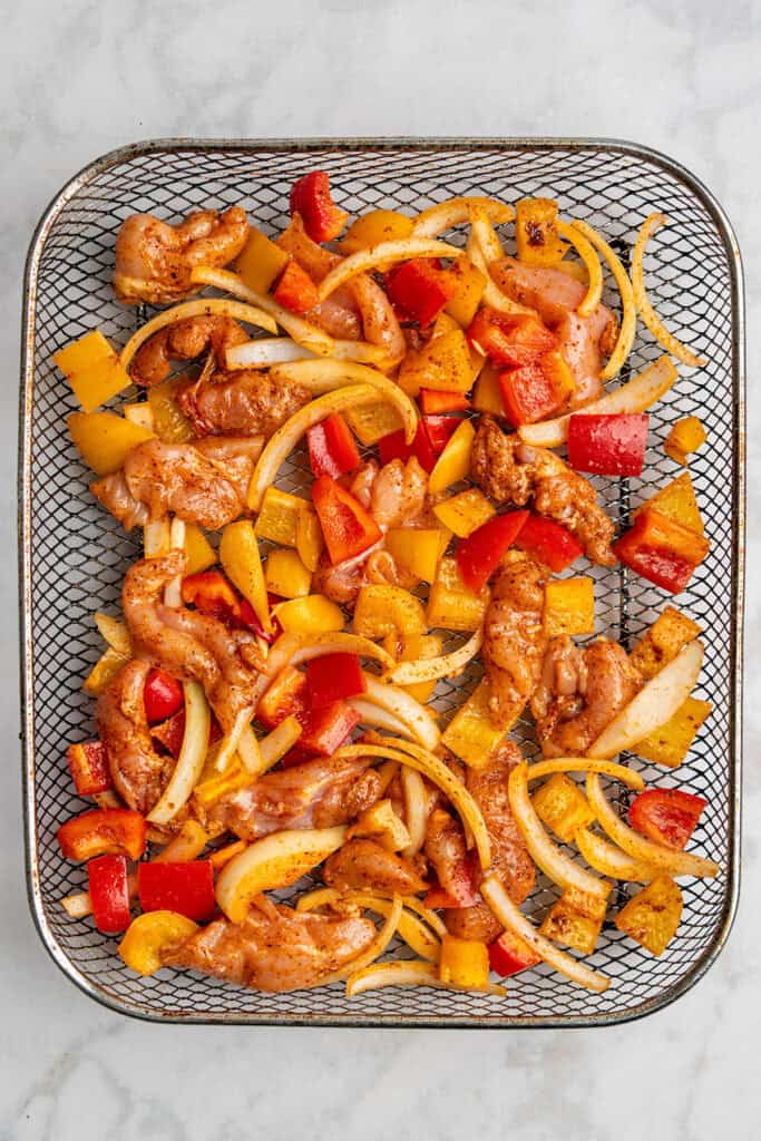 raw fajita mixture on an air fryer rack.