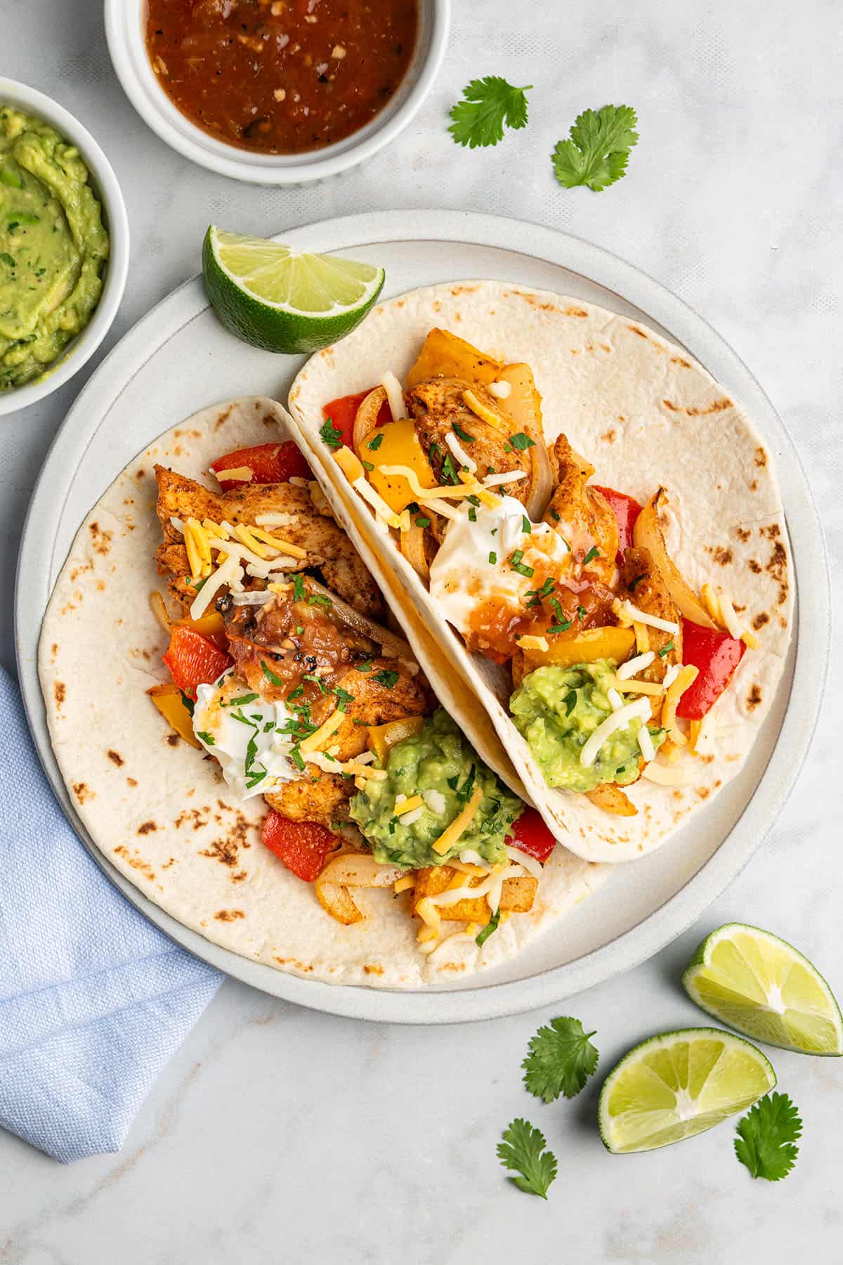 air fryer chicken fajitas on flour tortillas with sour cream and guacamole on top.
