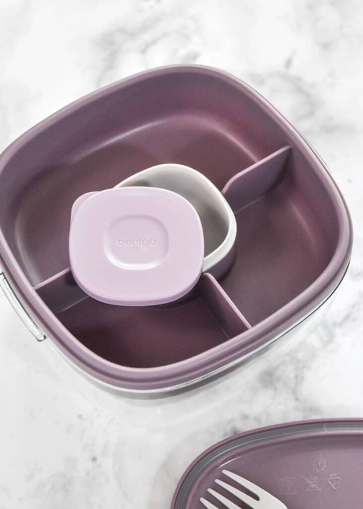 meal prep container with built in sauce cup and fork with pieces spread out.