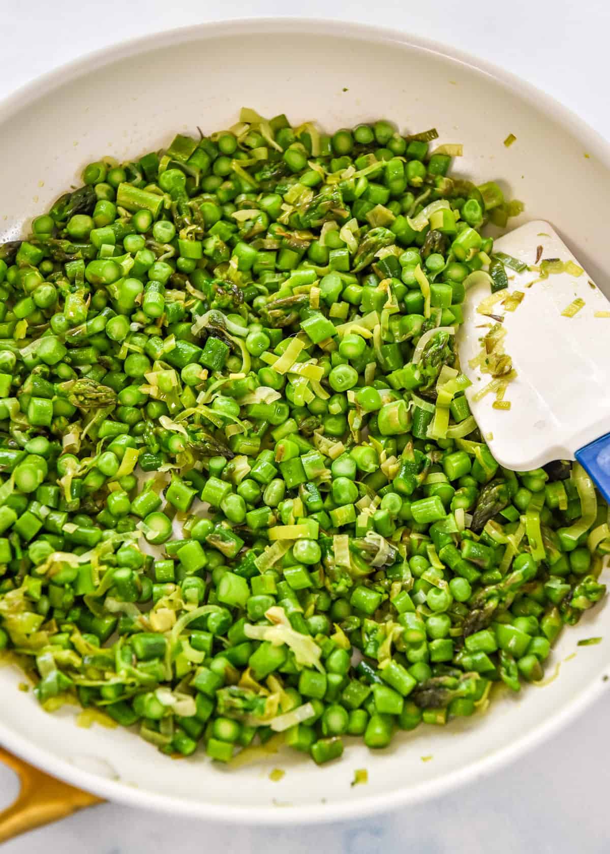 sauteed asparagus, leeks, and peas in a nonstick pan.