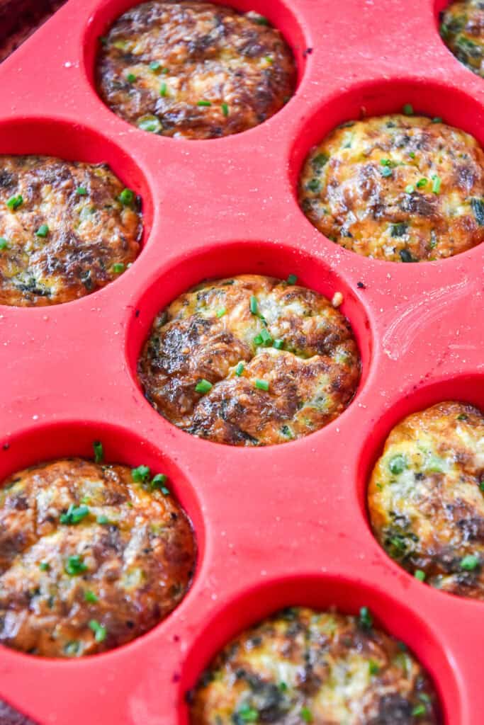baked crustless quiche in a red silicone muffin pan.