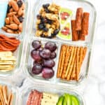 cheese, pretzels, grapes and granola in a glass meal prep container to make a DIY Adult Lunchable.