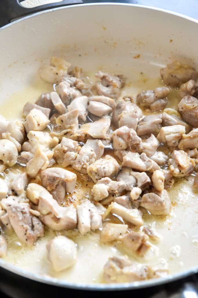 chicken chunks cooking in a pan on the stovetop.