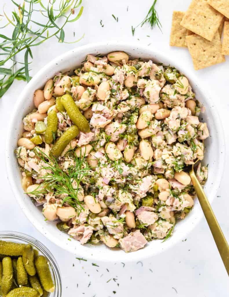 French-Style Tuna White Bean Salad in a bowl with fresh herbs and crackers on the side.